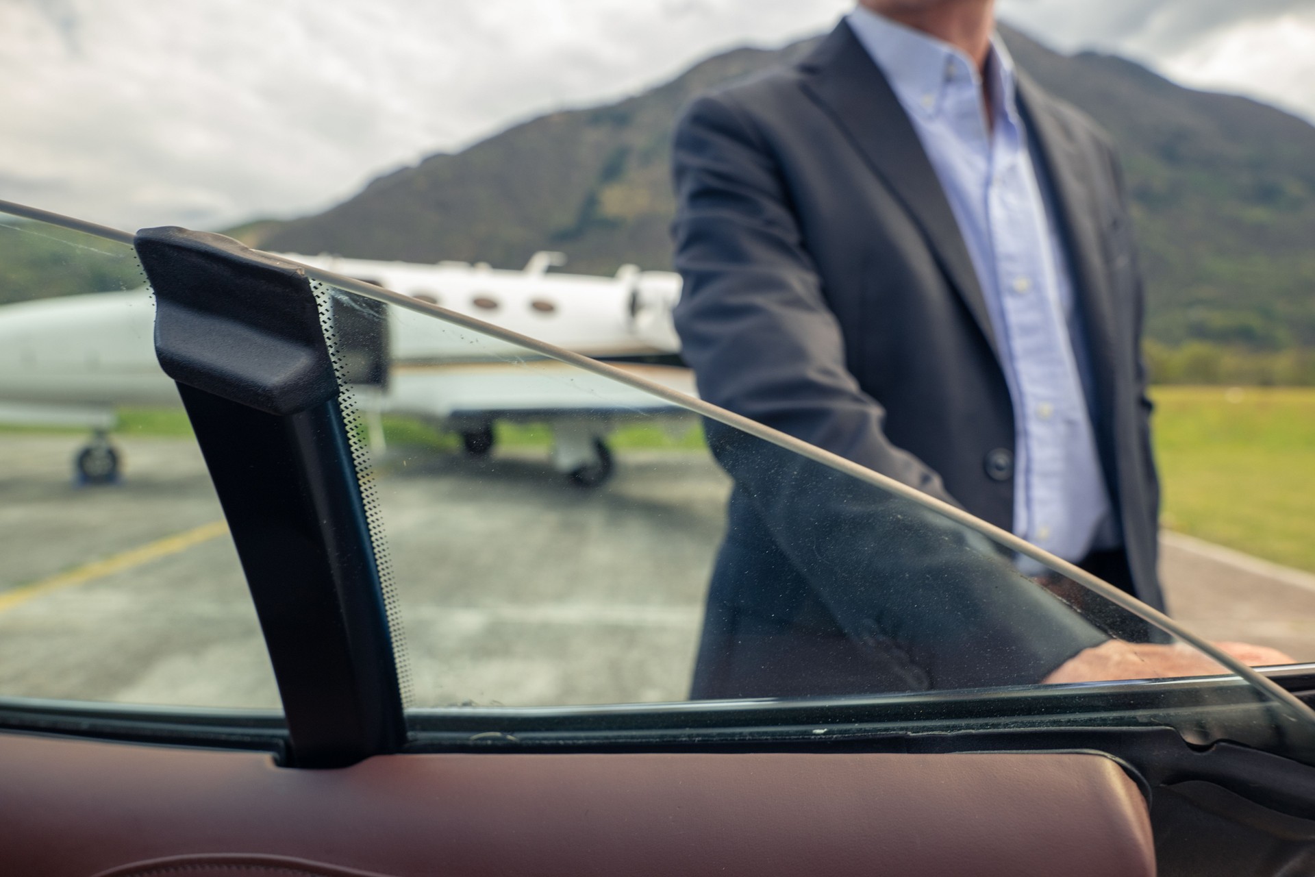 Unrecognisable driver opens car door, Private Jet on the runaway